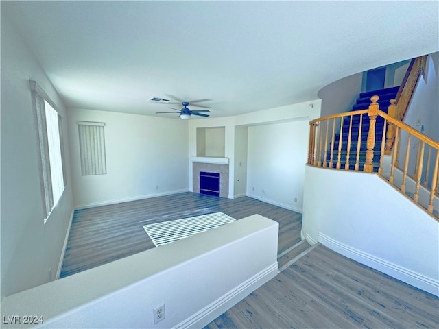 living room with a tiled fireplace, ceiling fan, and hardwood / wood-style flooring