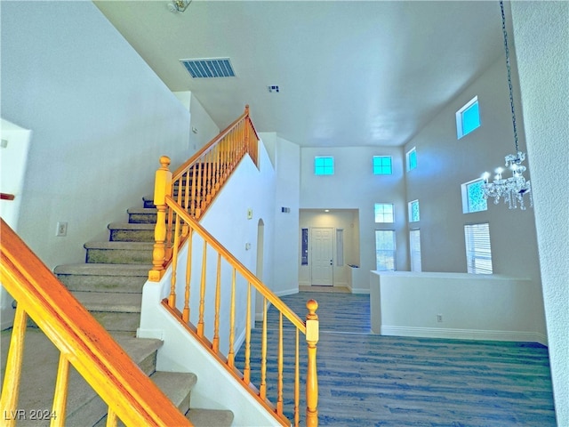 staircase with a high ceiling, hardwood / wood-style flooring, and a notable chandelier