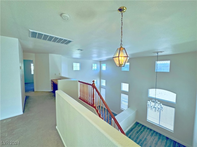 stairway featuring carpet, a wealth of natural light, and an inviting chandelier