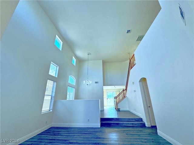 interior space with a high ceiling, dark hardwood / wood-style floors, and a notable chandelier