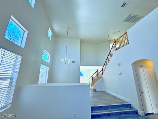 stairway featuring hardwood / wood-style flooring, a notable chandelier, and a high ceiling