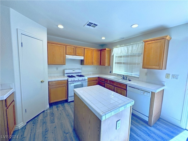 kitchen with tile counters, a center island, sink, hardwood / wood-style floors, and white appliances