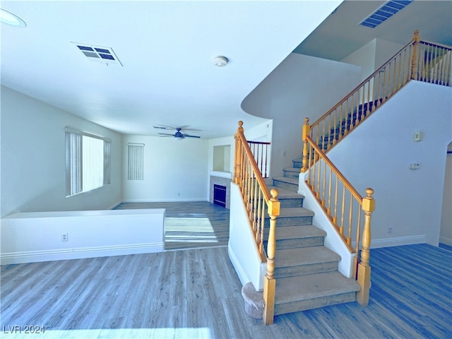 staircase with ceiling fan and wood-type flooring