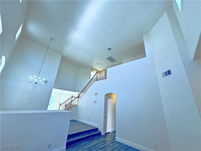 staircase with a chandelier, a high ceiling, and hardwood / wood-style flooring