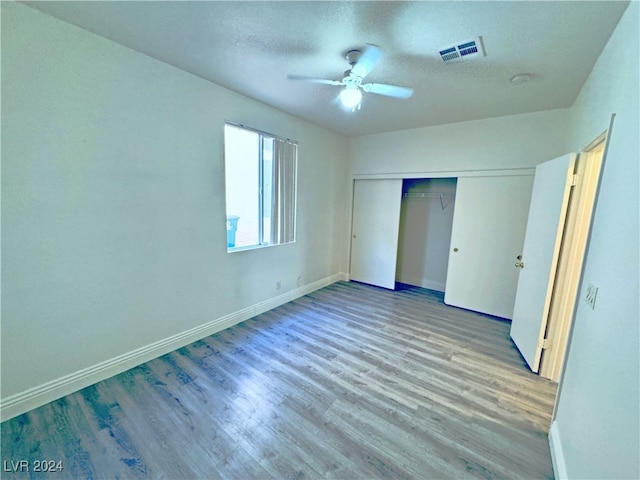 unfurnished bedroom featuring ceiling fan, light hardwood / wood-style floors, a textured ceiling, and a closet