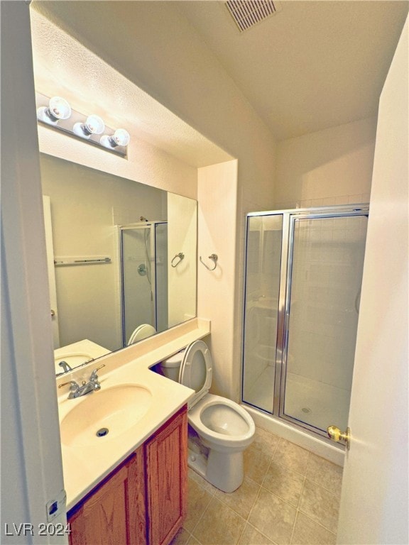 bathroom featuring tile patterned floors, vanity, toilet, and a shower with door