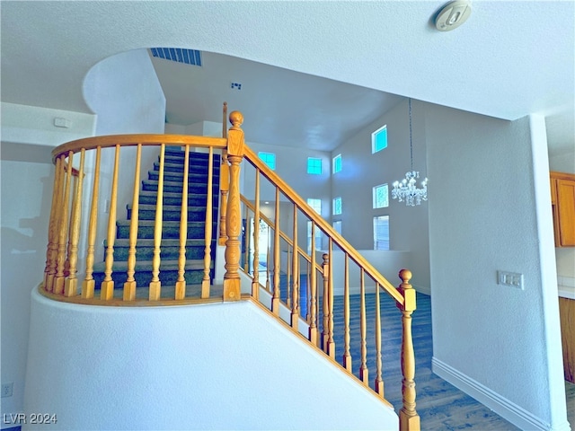 stairs featuring a textured ceiling, a notable chandelier, and hardwood / wood-style flooring