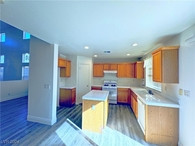 kitchen featuring hardwood / wood-style flooring, a center island, white appliances, and sink