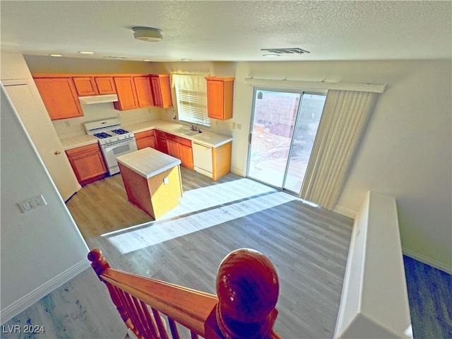 kitchen featuring a center island, sink, light hardwood / wood-style flooring, a textured ceiling, and white appliances