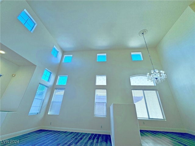 unfurnished living room with dark hardwood / wood-style flooring, a towering ceiling, and a notable chandelier