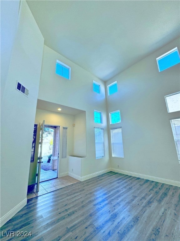 unfurnished living room with a towering ceiling and hardwood / wood-style flooring