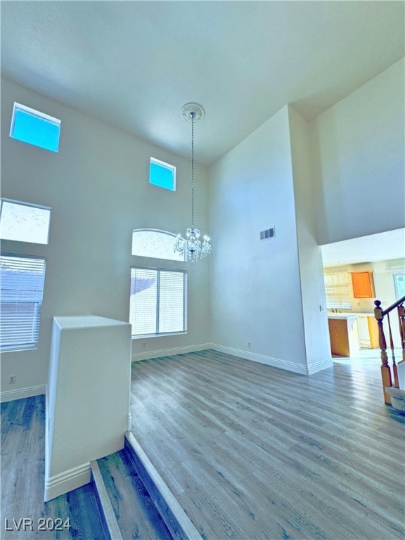 interior space with a high ceiling, hardwood / wood-style flooring, and an inviting chandelier