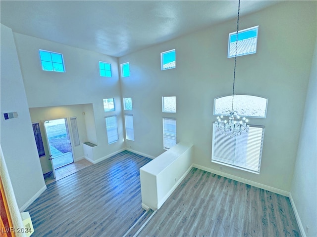 foyer entrance featuring a towering ceiling, hardwood / wood-style flooring, and a notable chandelier