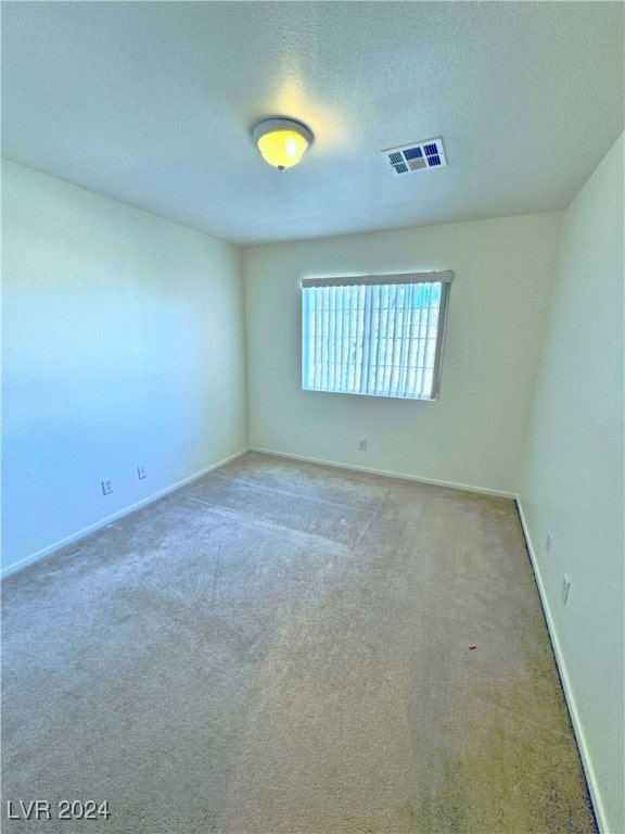 carpeted empty room featuring a textured ceiling