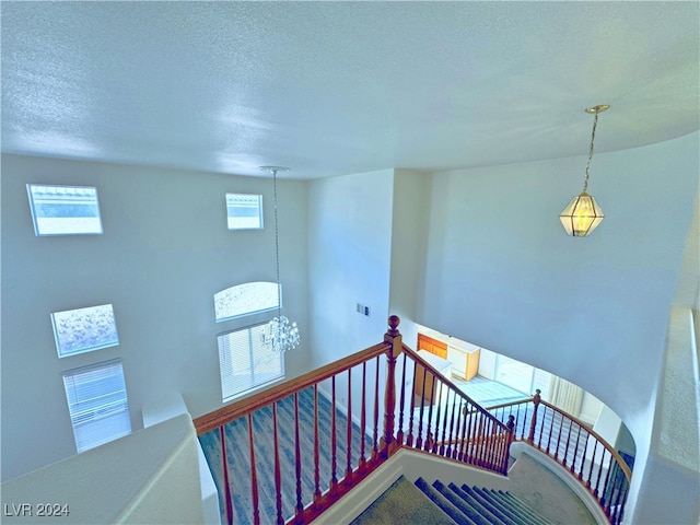 stairway featuring a notable chandelier and a textured ceiling