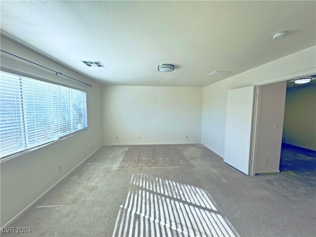 carpeted empty room featuring a textured ceiling