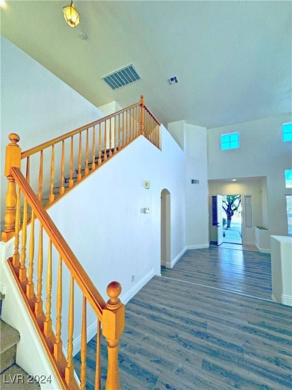 stairs featuring wood-type flooring and a high ceiling