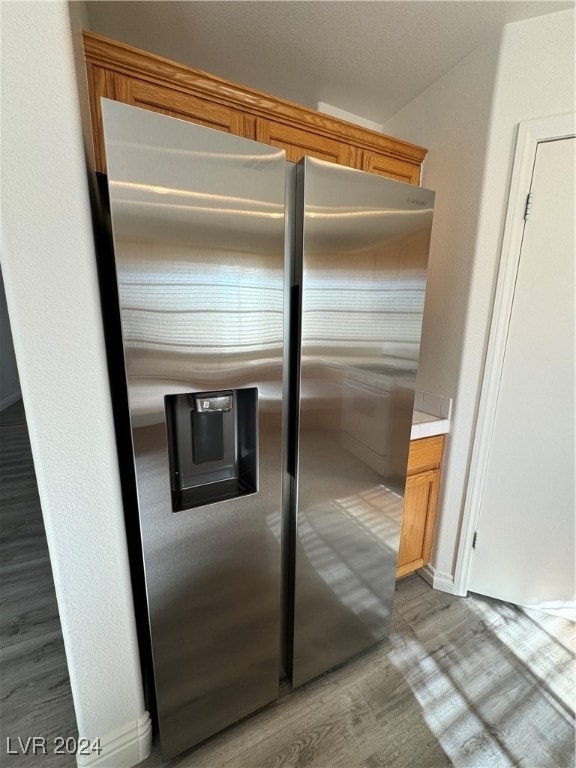 details featuring hardwood / wood-style flooring and stainless steel fridge with ice dispenser