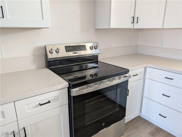 kitchen featuring light hardwood / wood-style flooring, white cabinets, and electric stove