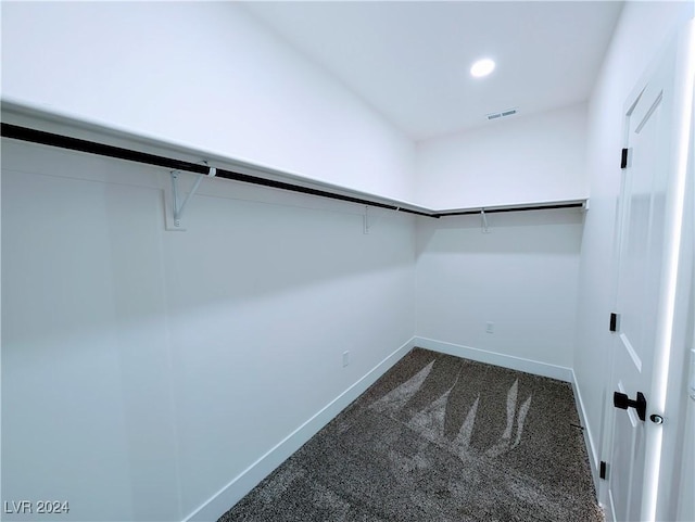 walk in closet with dark carpet