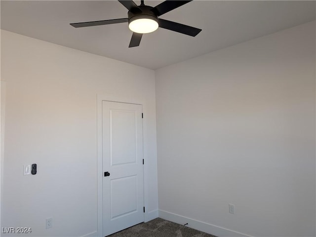 empty room with dark colored carpet and ceiling fan