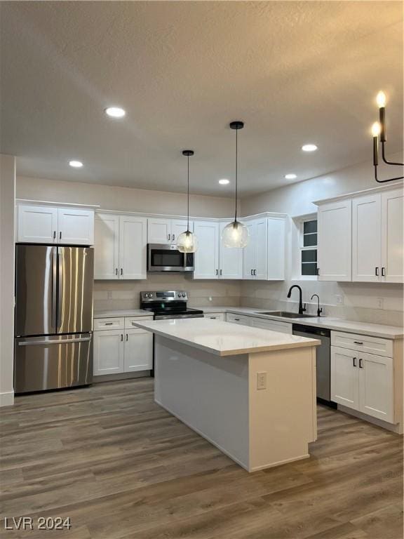 kitchen featuring decorative light fixtures, sink, stainless steel appliances, and white cabinetry