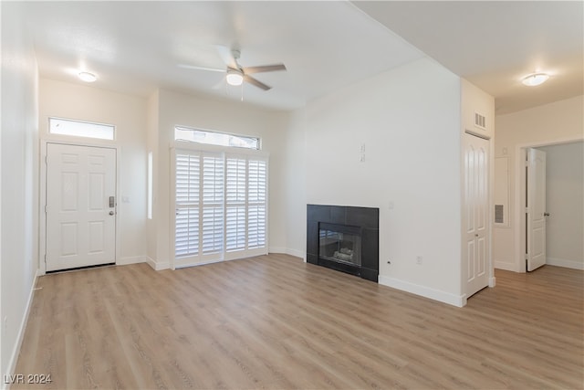 unfurnished living room featuring a fireplace, ceiling fan, and light wood-type flooring