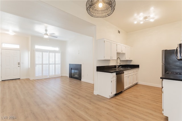 kitchen featuring stainless steel appliances, light hardwood / wood-style floors, sink, ceiling fan, and white cabinetry