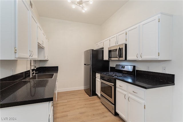 kitchen with appliances with stainless steel finishes, sink, light hardwood / wood-style floors, and white cabinets