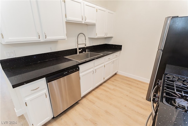 kitchen with white cabinets, light wood-type flooring, stainless steel appliances, and sink