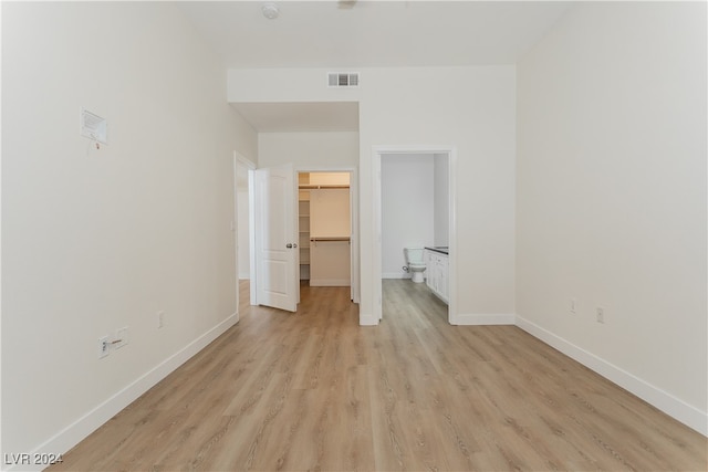 unfurnished bedroom with a closet, light wood-type flooring, and a walk in closet