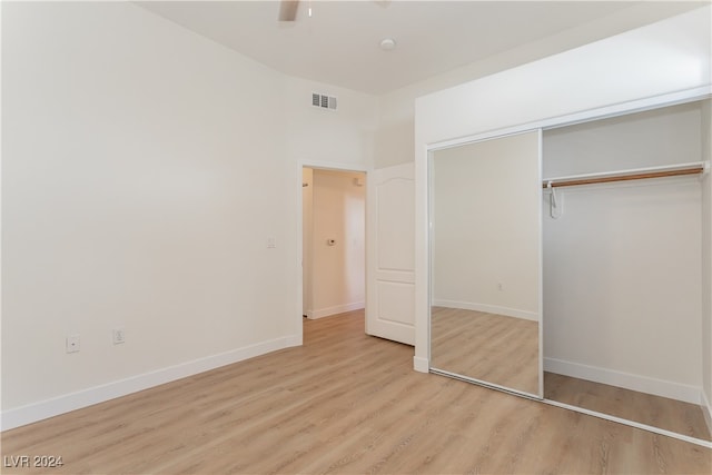 unfurnished bedroom featuring light wood-type flooring, ceiling fan, and a closet