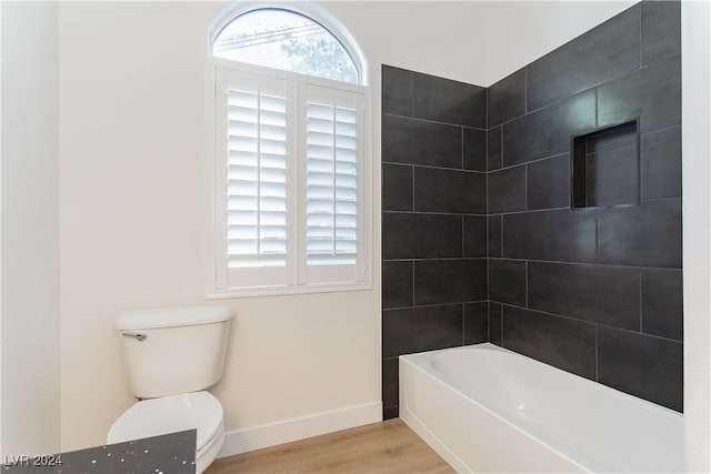 bathroom featuring toilet, tiled shower / bath, and hardwood / wood-style flooring