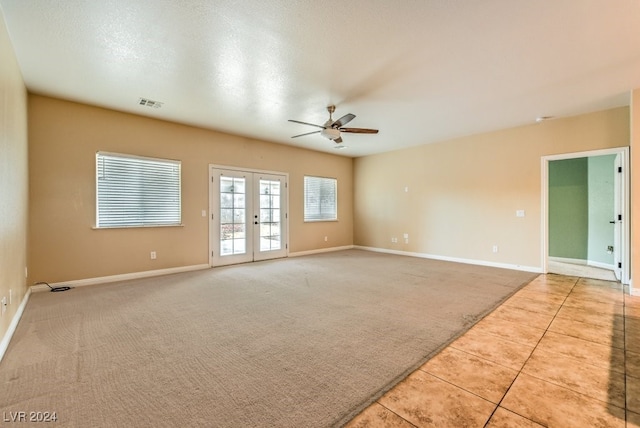 tiled empty room featuring ceiling fan, a textured ceiling, and french doors