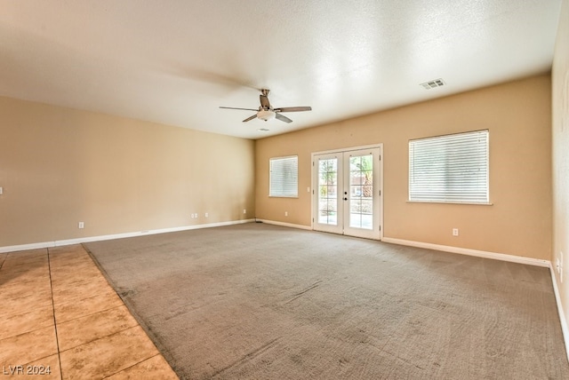 carpeted empty room with a textured ceiling, french doors, and ceiling fan