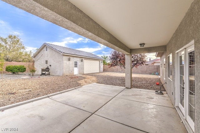 view of patio / terrace with a garage, an outdoor structure, and grilling area