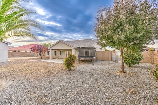 rear view of house featuring a trampoline and a patio