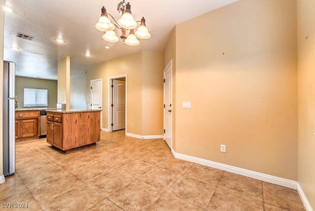 kitchen with light stone counters, appliances with stainless steel finishes, light tile patterned floors, decorative light fixtures, and a chandelier