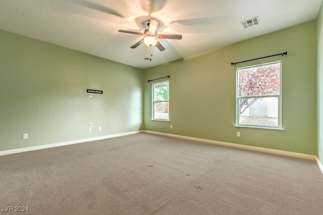 carpeted empty room with a wealth of natural light and ceiling fan