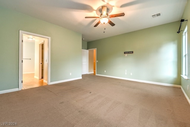 unfurnished bedroom with multiple windows, light carpet, ceiling fan, and ensuite bathroom