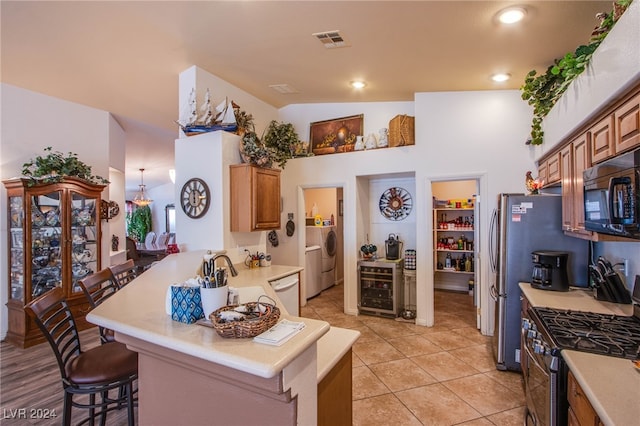 kitchen with lofted ceiling, beverage cooler, a kitchen bar, kitchen peninsula, and gas stove