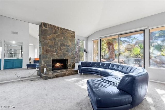 living room featuring a stone fireplace, vaulted ceiling, and light carpet