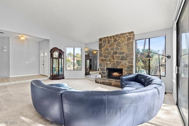 carpeted living room featuring vaulted ceiling, a wealth of natural light, and a stone fireplace