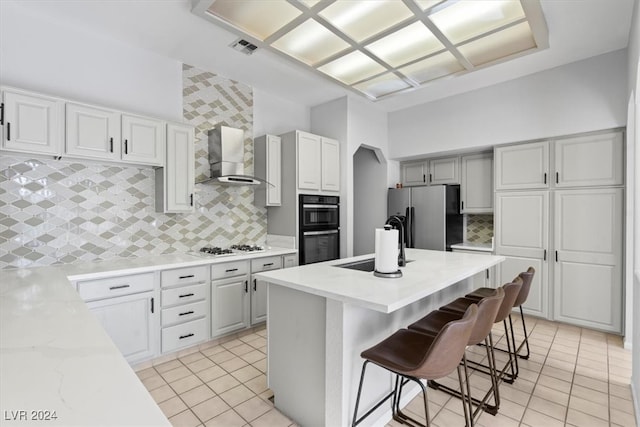 kitchen featuring stainless steel fridge with ice dispenser, wall chimney range hood, a kitchen bar, and tasteful backsplash