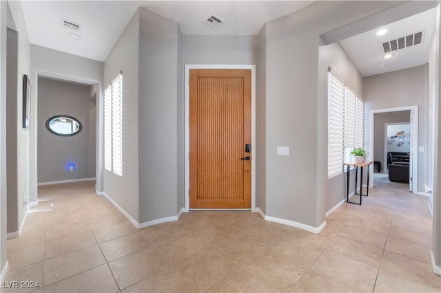 foyer entrance featuring light tile patterned floors, visible vents, and baseboards