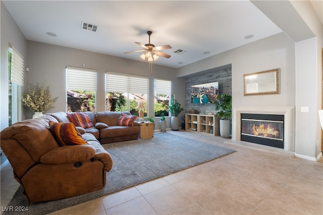 living room with a glass covered fireplace, light tile patterned flooring, a ceiling fan, and visible vents