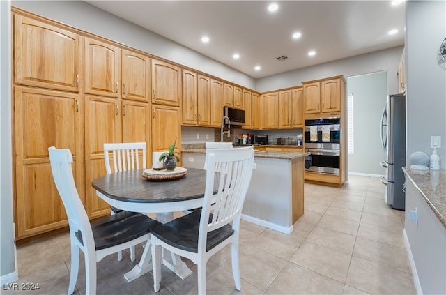 kitchen featuring light tile patterned floors, light stone counters, appliances with stainless steel finishes, and recessed lighting