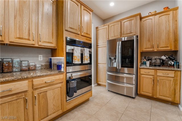 kitchen featuring stone countertops, stainless steel appliances, and light tile patterned flooring