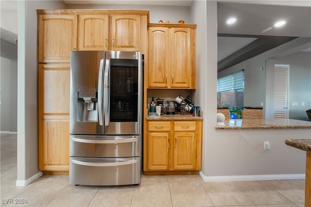 kitchen featuring light stone counters, light tile patterned flooring, and stainless steel refrigerator with ice dispenser