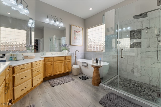 full bath with wood finish floors, vanity, a freestanding bath, and a shower stall